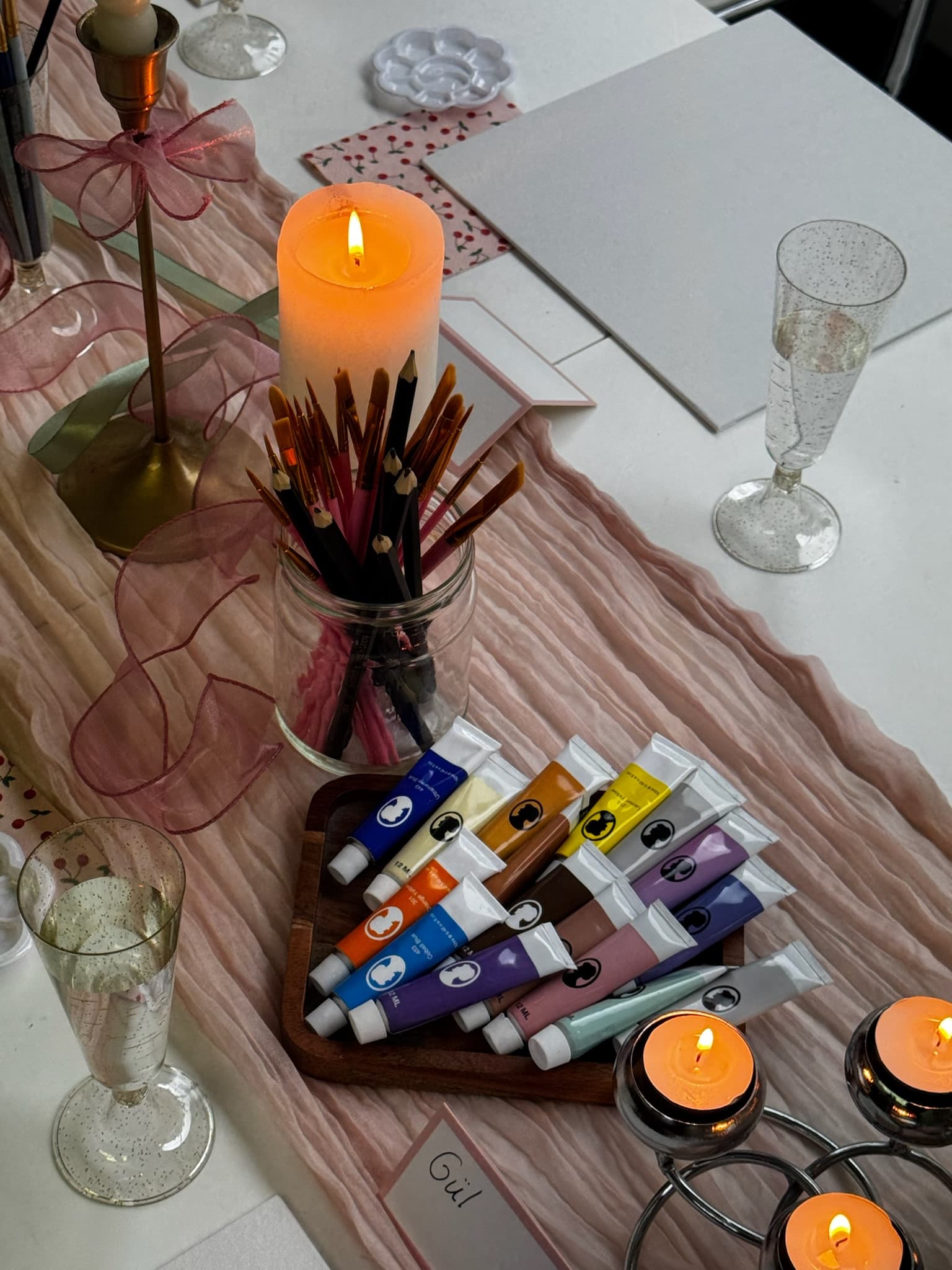 A table set up with paints, brushes and candles for a private event